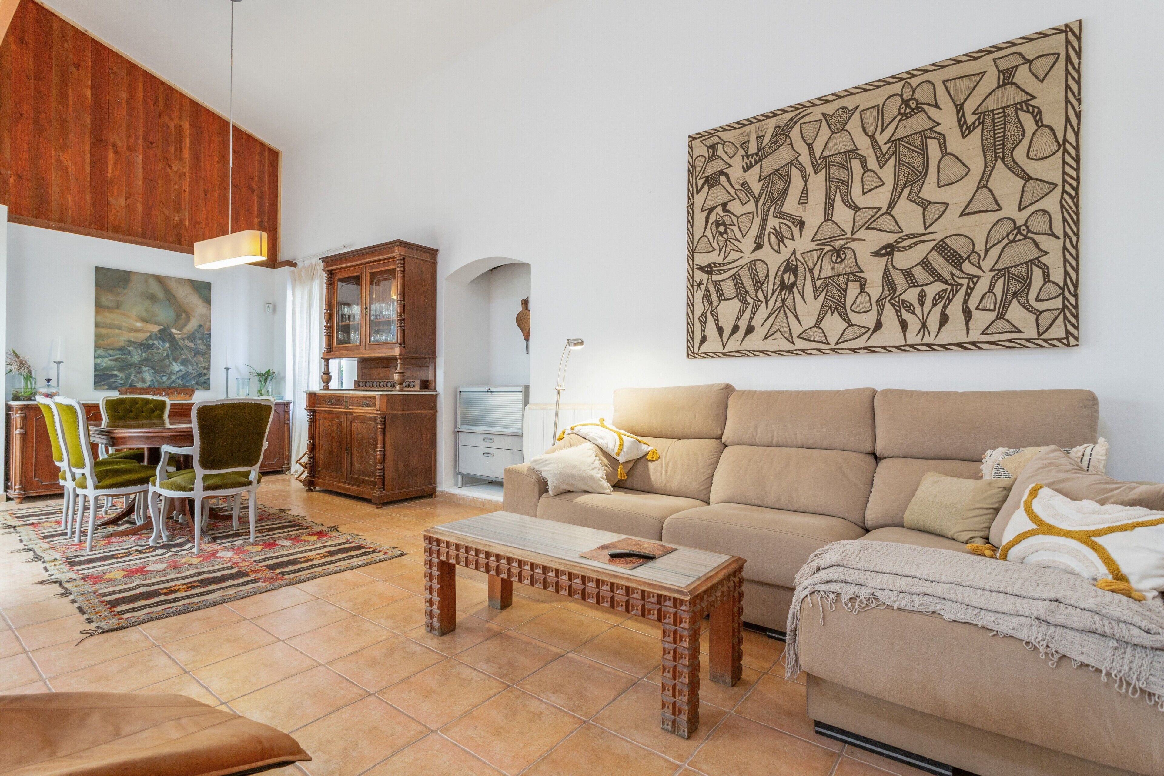 A living room with a sofa, a coffee table, and a dining area with chairs and a cabinet.
