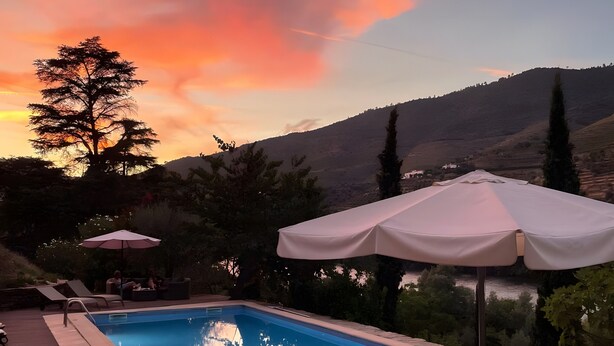 A swimming pool with lounge chairs and umbrellas, surrounded by a hilly landscape. - Casa Rosa Chalet with Shared Pool, Wi-Fi and Air Conditioning (São João da Pesqueira)