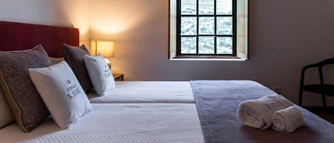Habitación de hotel con dos camas, una ventana, una lámpara y una silla.