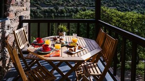 A wooden table with breakfast items, surrounded by chairs, overlooking a scenic landscape. - Casa Rosa Chalet with Shared Pool, Wi-Fi and Air Conditioning (São João da Pesqueira)