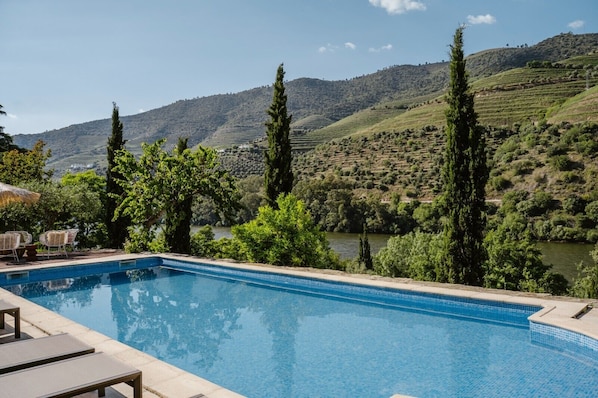 Une piscine avec vue sur une rivière et des collines.