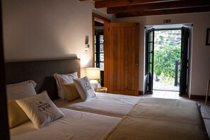 Habitació d'hotel amb dos llits, una porta de fusta, una finestra i una camèra de nit amb una làmpada.