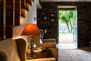 A room with a stone wall, a wooden staircase, a lamp, a chair, and a door leading outside. - Chalet 'Casa Verde' with Shared Pool, Wi-Fi and Air Conditioning (São João da Pesqueira)