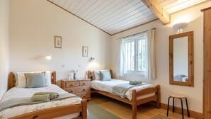 Une chambre à coucher avec deux lits en bois, une commode, un miroir et une fenêtre avec des rideaux.