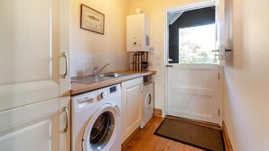 Une cuisine compacte équipée d’un lave-linge, d’un évier et d’un chauffe-eau.