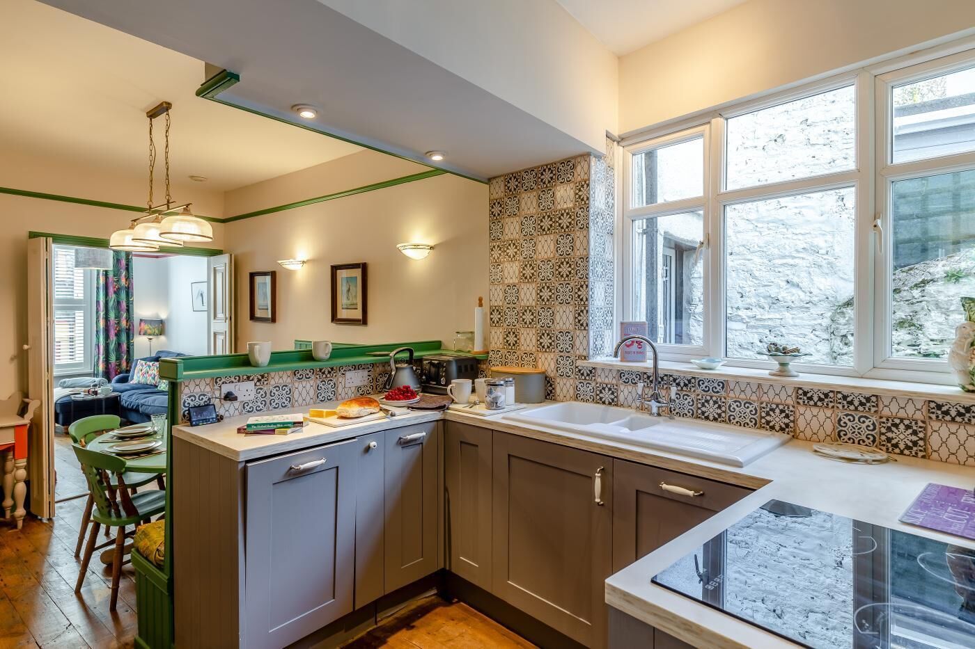 A compact kitchen with a dining area, a window with a view, and a green accent wall.