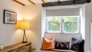 Una habitació amb seients a la finestra, una làmpada, un taulell de fusta i un quadre al mur.