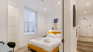 Une chambre à coucher avec un lit, une fenêtre, un bureau et une chaise.