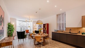 Une cuisine moderne avec un coin repas, un plancher en bois et une grande fenêtre.