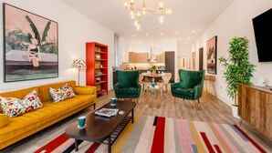 Un salon moderne avec un canapé jaune, des fauteuils verts, une table basse et un tapis à rayures.