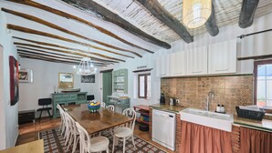 A kitchen with a wooden table, white cabinets, and a tiled backsplash.