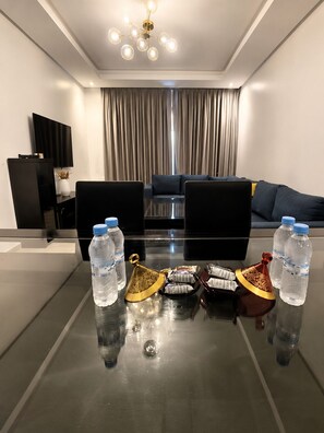 Ein modernes Wohnzimmer mit einem Glastisch, einer Couch, einem Fernseher und einer Vorhangwand.
