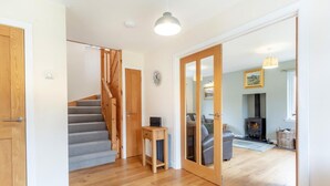 Un escalier menant à un espace de vie comprenant une cheminée, un ordinateur portable posé sur une petite table et un canapé.