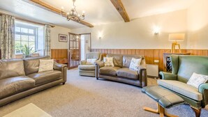 A living room with a brown leather sofa, two armchairs, a bench, a chandelier, and a lamp. - 4 Bed in Builth Wells (oc-t38238) (Treflys)