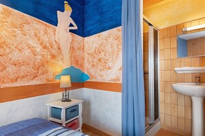 A bathroom with a shower, a sink, and a wall with a mural.