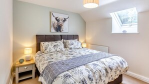 Een slaapkamer met een bed, nachtlampjes, een klok, een raam en een plafondlamp.