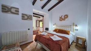 A bedroom with a bed, a radiator, a wooden stool, and a window with curtains. - Luxury bedroom in Los Bermejales with a view of the pool. (Fornes)