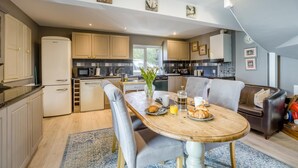 Una cucina moderna con zona pranzo, caratterizzata da un tavolo in legno, sedie e la tavola apparecchiata per la colazione.