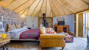 Un'accogliente stanza ben illuminata con un letto, un divano, un armadietto in legno e un televisore.
