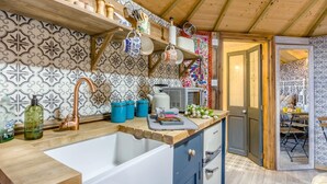 Una cucina con piano di lavoro in legno, lavello e fornello. Sul piano ci sono contenitori blu, un bollitore e un forno a microonde.