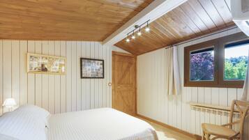 A bedroom with a bed, a chair, a wooden door, and a window with a view.