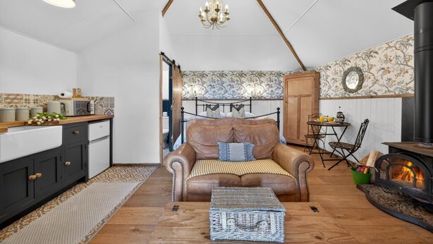 Ein gemütliches Wohnzimmer mit einer Ledersofa, einem Kamin, einem Esstisch mit Stühlen und einer Küchenzeile mit Schränken und einer Pendelleuchte.