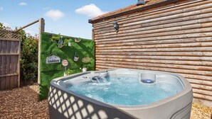 Ein Whirlpool in einem Gartenbereich mit Holzzaun und einem Schild mit der Aufschrift 'Welcome to Garden'.