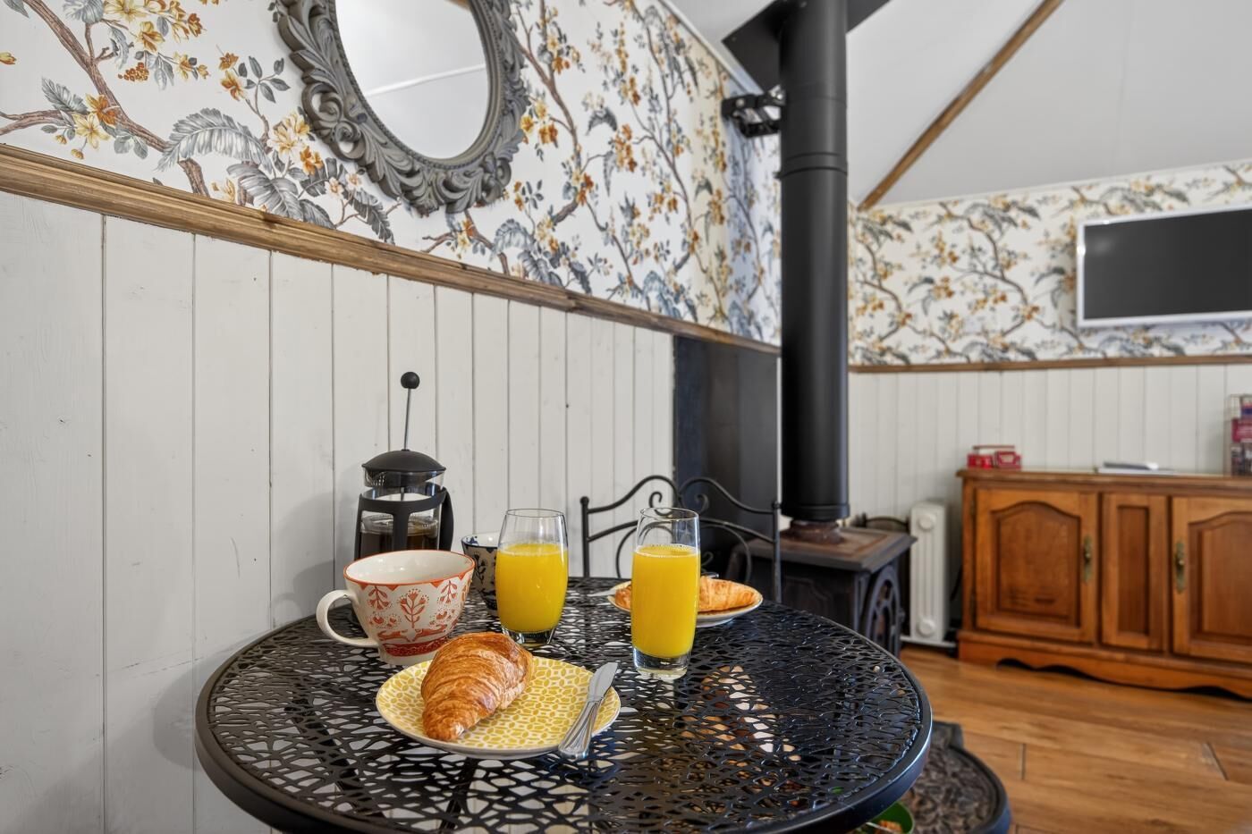 Een eettafel met een croissant, een mok en een glas sinaasappelsap.