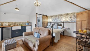 Ein gemütliches Zimmer mit einer Couch, einem Bett, einem Esstisch und einer Küchenzeile.