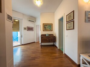 A hallway with wooden flooring, a wooden cabinet, and framed artwork on the walls. - Top floor with a spacious terrace, parking space, air conditioning, and an elevator (Lerici)
