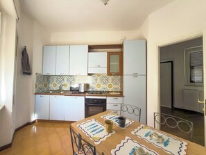 A compact kitchen with white cabinets, a tiled backsplash, and a dining area with a table set for two. - Top floor with a spacious terrace, parking space, air conditioning, and an elevator (Lerici)
