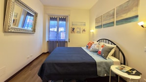Une chambre à coucher avec un lit, une table de chevet, un miroir et des œuvres d’art accrochées aux murs.