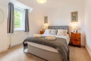 A bedroom with a bed, two bedside tables, a window with curtains, and wall art. - 3 Bed in Dingwall (oc-m39032) (Dingwall)