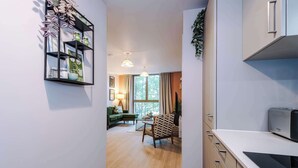 Una cucina moderna con un forno a microonde Bosch, un'area pranzo con un divano verde e una libreria con oggetti decorativi.