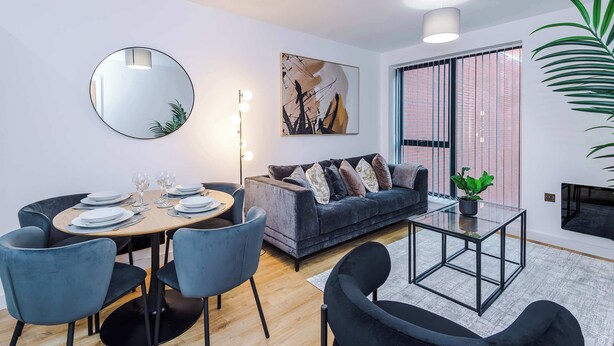Ein modernes Wohnzimmer mit einem runden Esstisch, einer grauen Couch und einem Glastisch.
