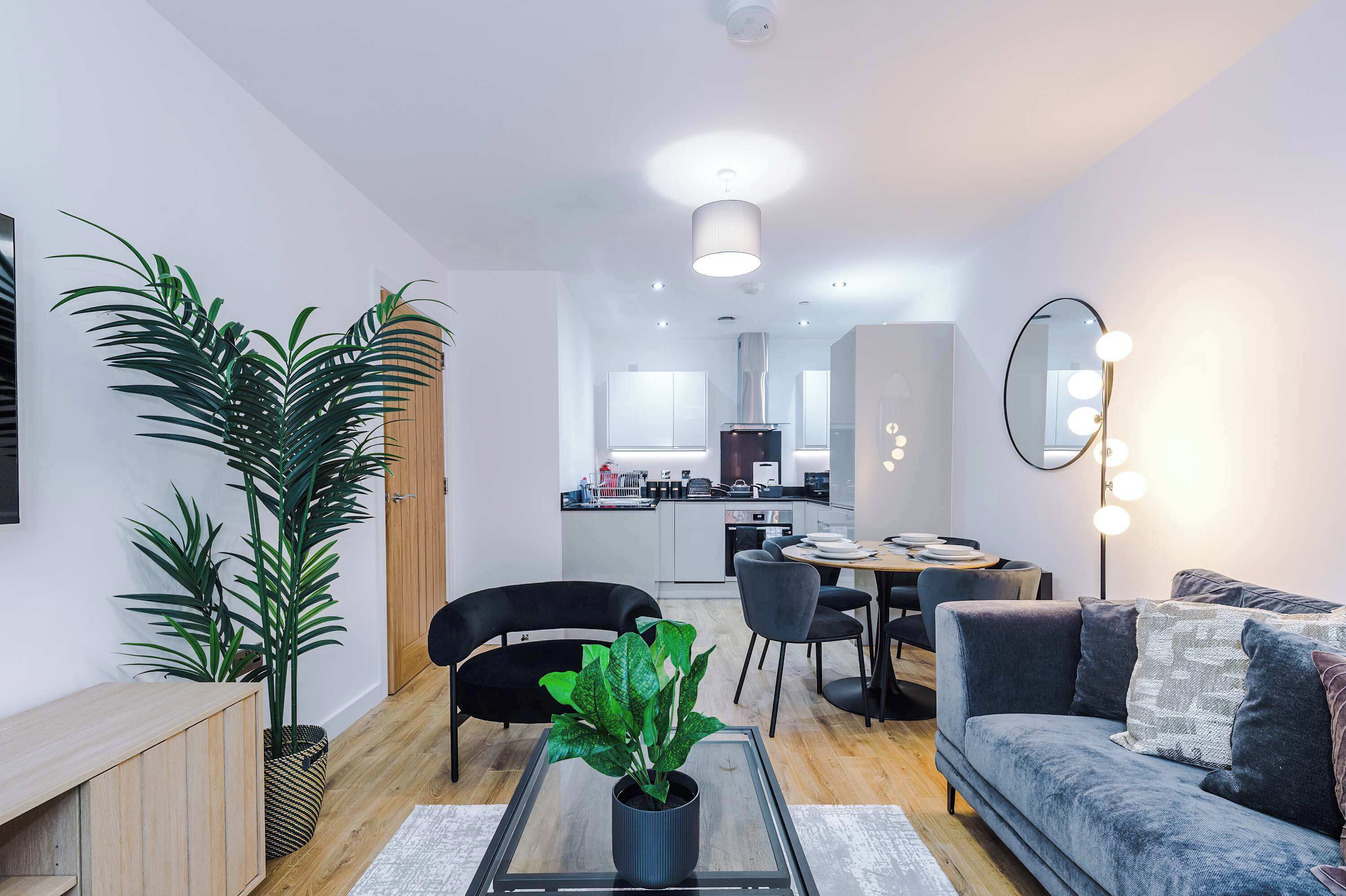 Een moderne woonkamer met een bank, salontafel en potplanten.