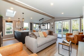 Uma sala de estar espaçosa com sofá, poltronas, mesa de jantar e área de cozinha com balcão.