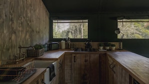 A rustic kitchen with wooden cabinets, a sink, a kettle, and a window with a view of trees. - 3 Bed in Hintlesham (oc-r39060) (Hintlesham)