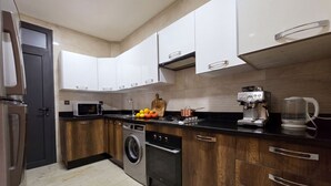Een moderne keuken met een wasmachine, een koffiezetapparaat en een magnetron.