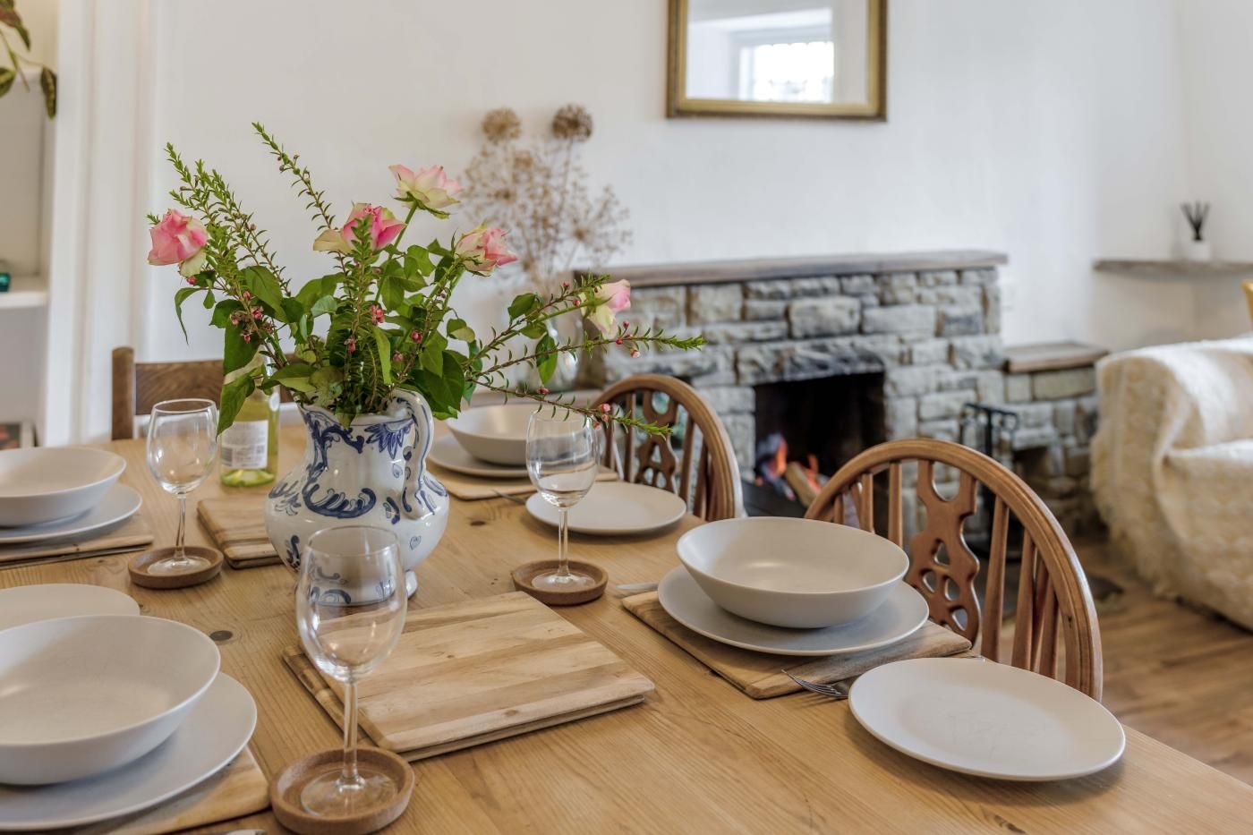 Une table à manger dressée avec des assiettes, des verres et un vase rempli de fleurs.