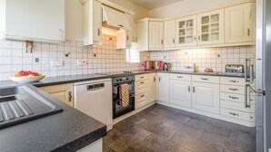 Eine Küche mit weißen Schränken, einem Geschirrspüler, einem Backofen, einer Mikrowelle und einem Kühlschrank.