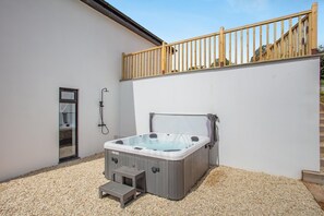 A hot tub in a covered outdoor area with a wooden deck above, a shower, and a small step leading to the tub. - 4 Bed in Bishops Tawton (oc-s35786) (Bishop's Tawton)
