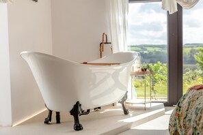 A white clawfoot bathtub in a room with a large window overlooking a green landscape. - 4 Bed in Bishops Tawton (oc-s35786) (Bishop's Tawton)