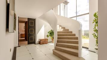 A modern interior with a spiral staircase, a large window, and a door leading to another room.