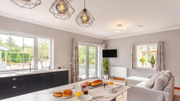 A modern kitchen with a marble countertop, breakfast setup, and a view of the outdoors.
