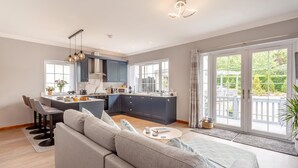 A modern kitchen with dark blue cabinets, a central island, and a dining area with bar stools.