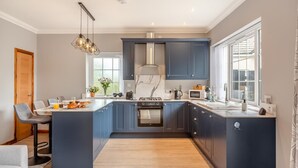 A modern kitchen with a central island, built-in appliances, and a large window providing natural light.