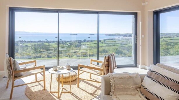 A room with a large sliding glass door, a round table with chairs, and a sofa. - 5 Bed in Mynytho (oc-t39070) (Mynytho)