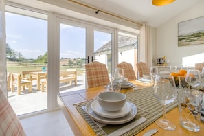 A dining area with a table set for four, chairs, and a view of the outdoors.