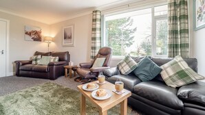 Ein gemütliches Wohnzimmer mit einem Ledersofa, zwei Sesseln, einem Couchtisch und einem Teppich.